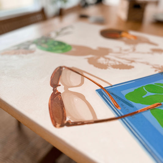 Colorful vibrant and bright Original oil painting of a glass with florals, sunglasses and a Matisse book with strong shadows. The artwork conveys feelings of a calm and quiet afternoon, relaxing and taking time to oneself