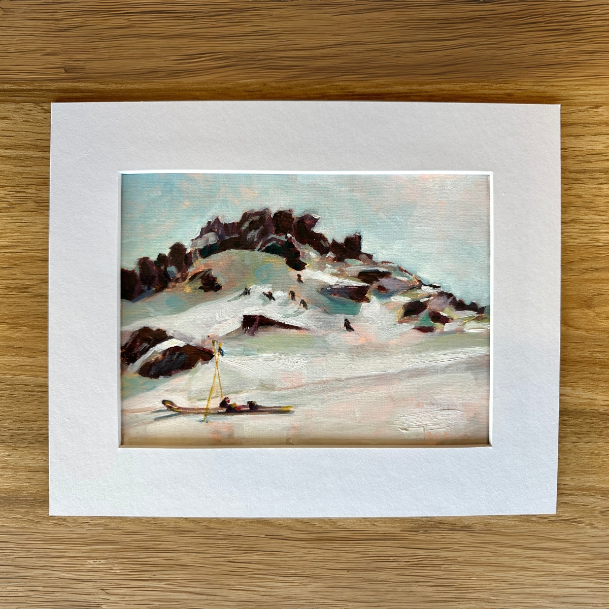 Art print of a snowy landscape with a small figure on a wooden surface