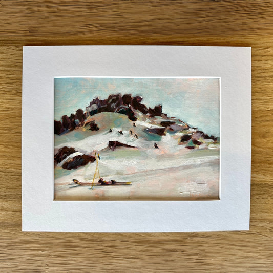 Art print of a snowy landscape with a small figure on a wooden surface