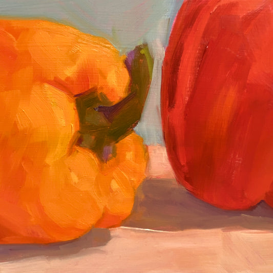 close up of an image of red and orange capsicum oil painting on a wooden panel with light grey-blue background and beige table