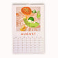 2024 art wall calendar in A3 size for the month of August, featuring a still life oil painting of fruits such as an orange papaya, a green rock melon, yellow lemon slices and limes on a creamy background with strong leaves shadows
