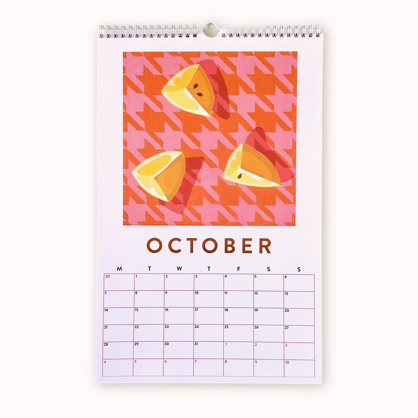 2024 art wall calendar in A3 size for the month of October, featuring a still life oil painting of yellow lemon slices on a pink and burnt orange houndstooth patterned background