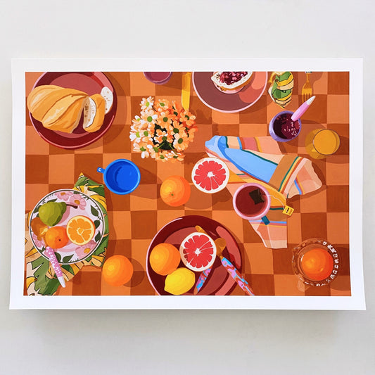 photo of a paper print of a breakfast setup with oranges, lemons, tea towels, cutlery by kip and co, and flowers and cups on a chequered tablecloth background