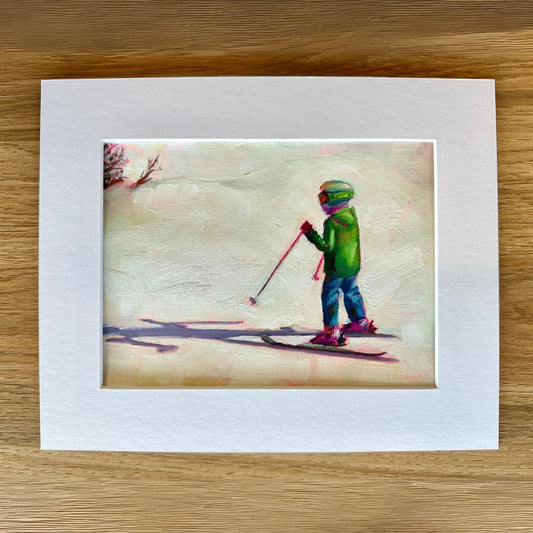 Framed artwork of a child skiing on a wooden surface