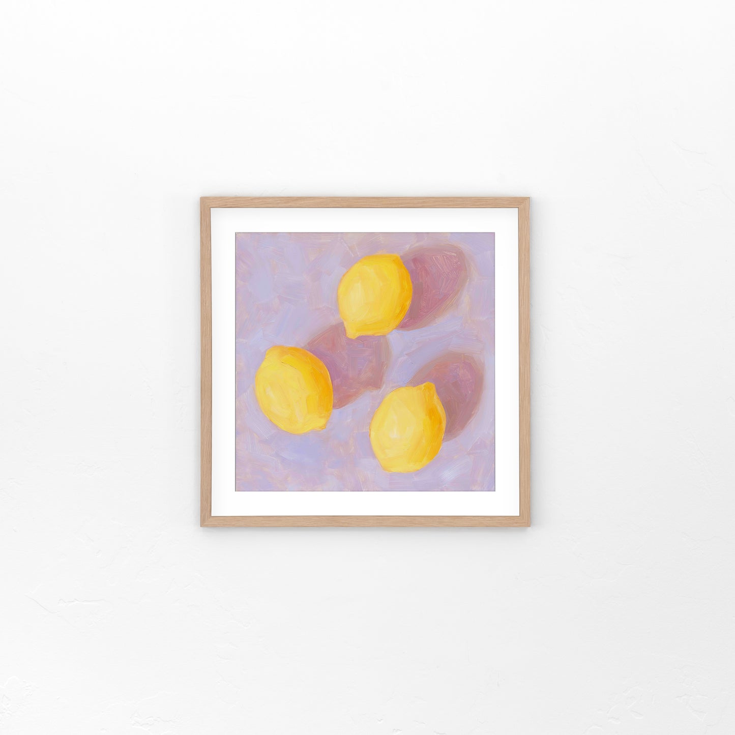 lifestyle photo of a fine art paper print of an original oil painting of three vibrant lemons with strong pink shadows on a textured lilac background
