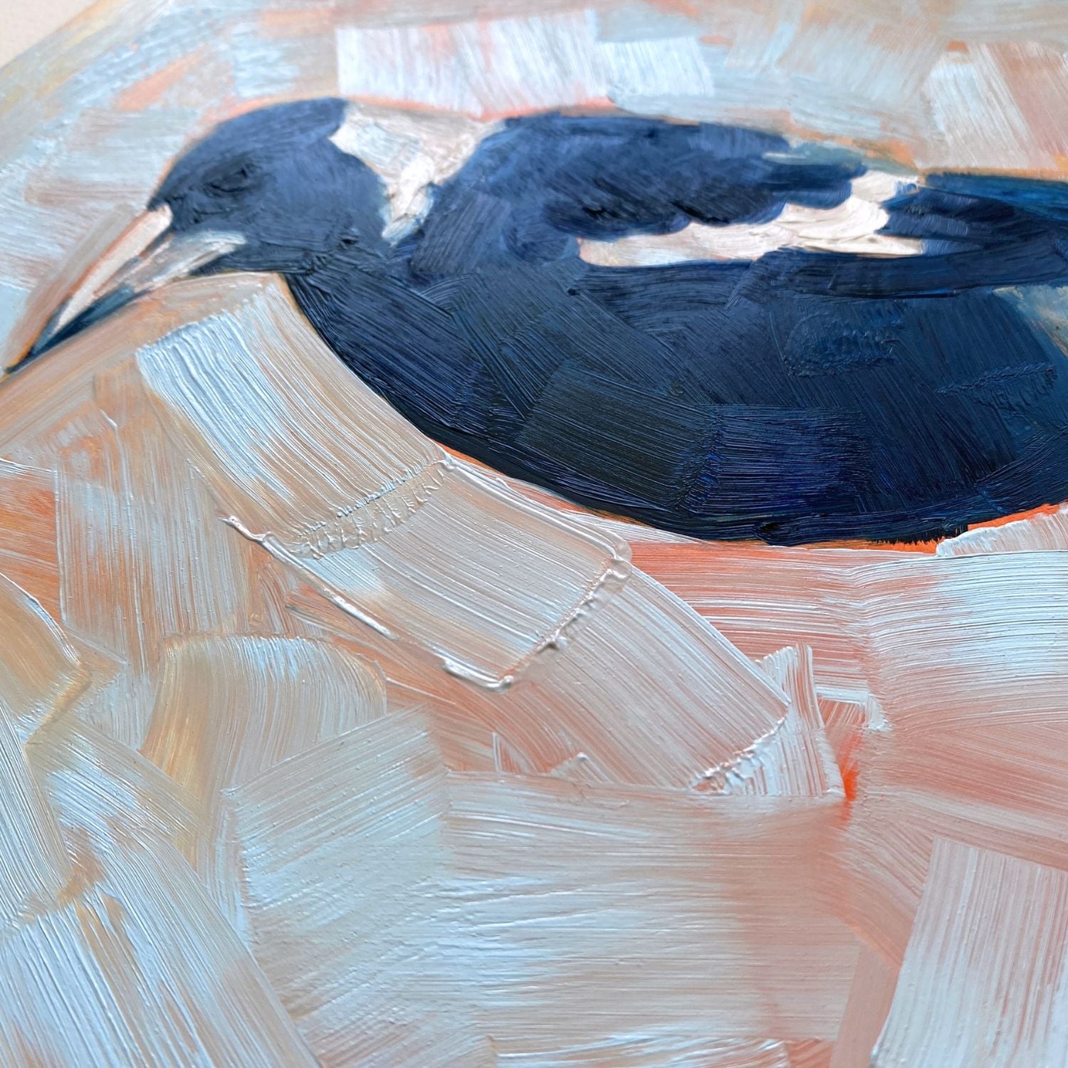 closeup of an original oil painting of a navy blue and white magpie on a textured sky blue background where you can see orange coming through
