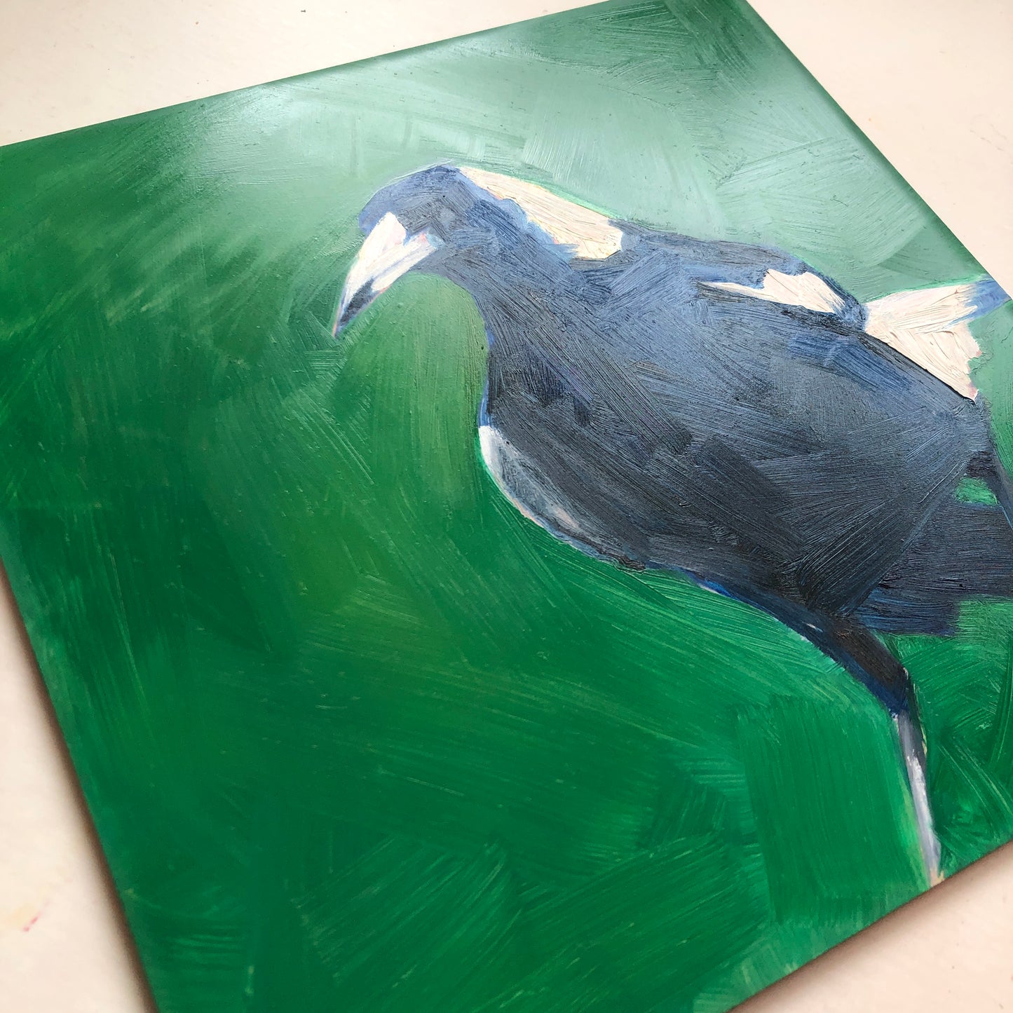 an original oil painting of a navy blue magpie on an emerald green background