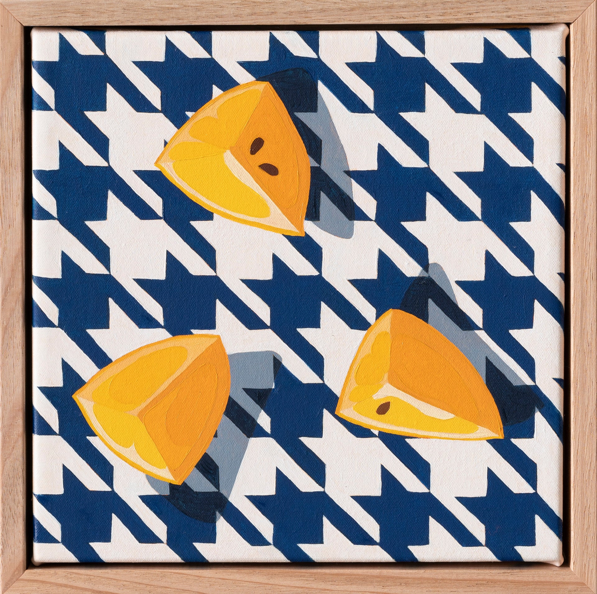 an original oil painting of three wedges of yellow lemons on a navy blue and white houndstooth background with blue-grey shadows framed in American Ash timber shadow box