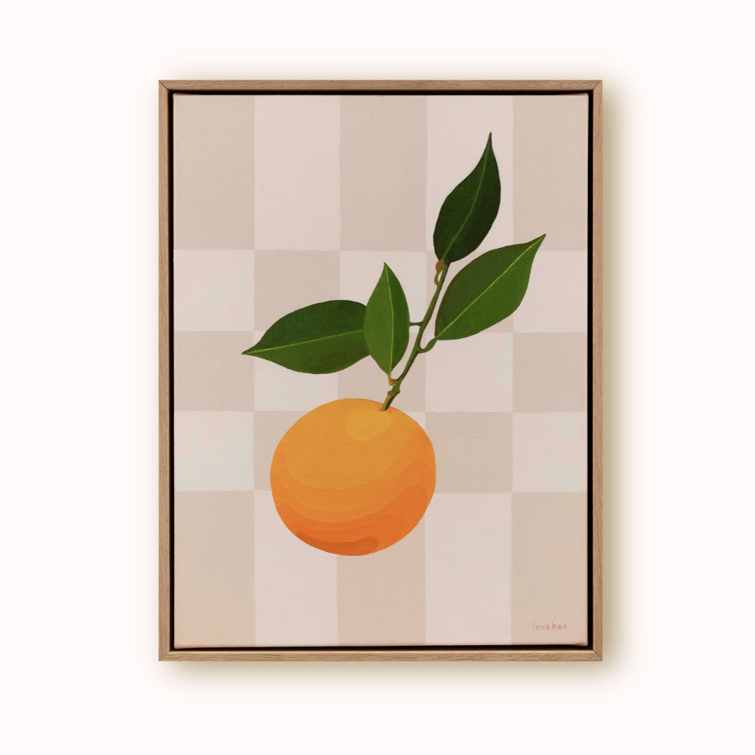 Framed artwork of an orange with leaves on a checkered background