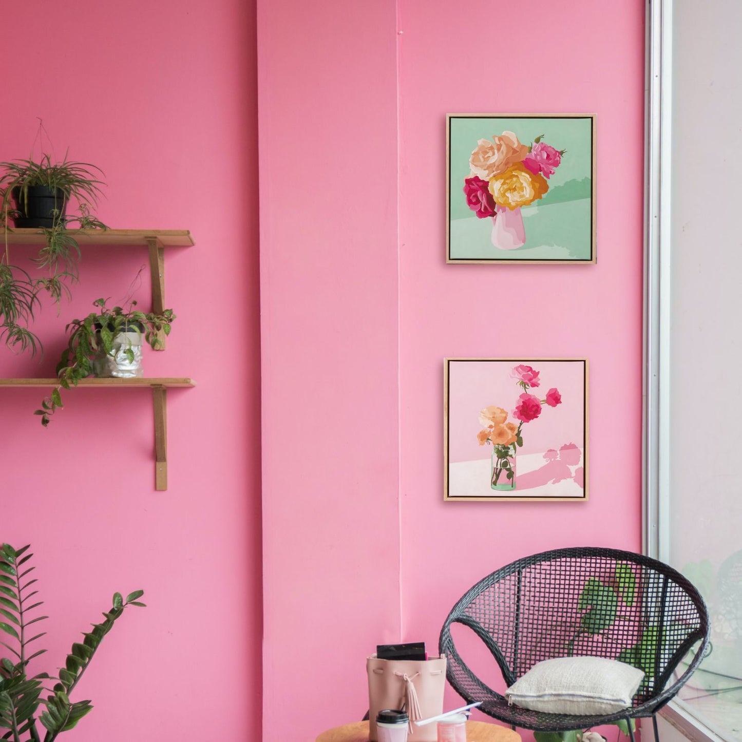 Lifestyle photo of original oil paintings hanging on a pink wall surrounded by plants and a chair next to a window