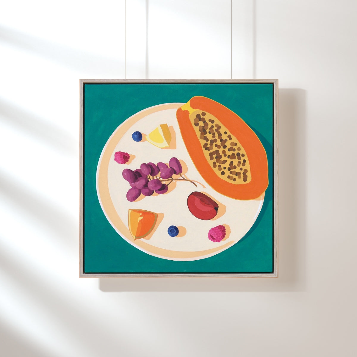 Framed artwork of a colorful fruit plate on a white wall