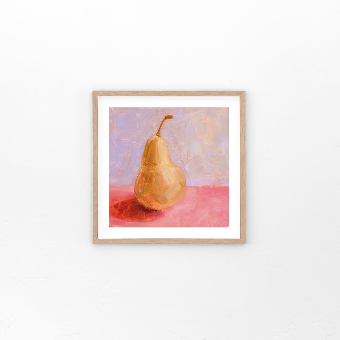 lifestyle photo of a fine art framed paper print of a yellow pear with strong red-pink shadows on a textured pink surface and a textured lilac background