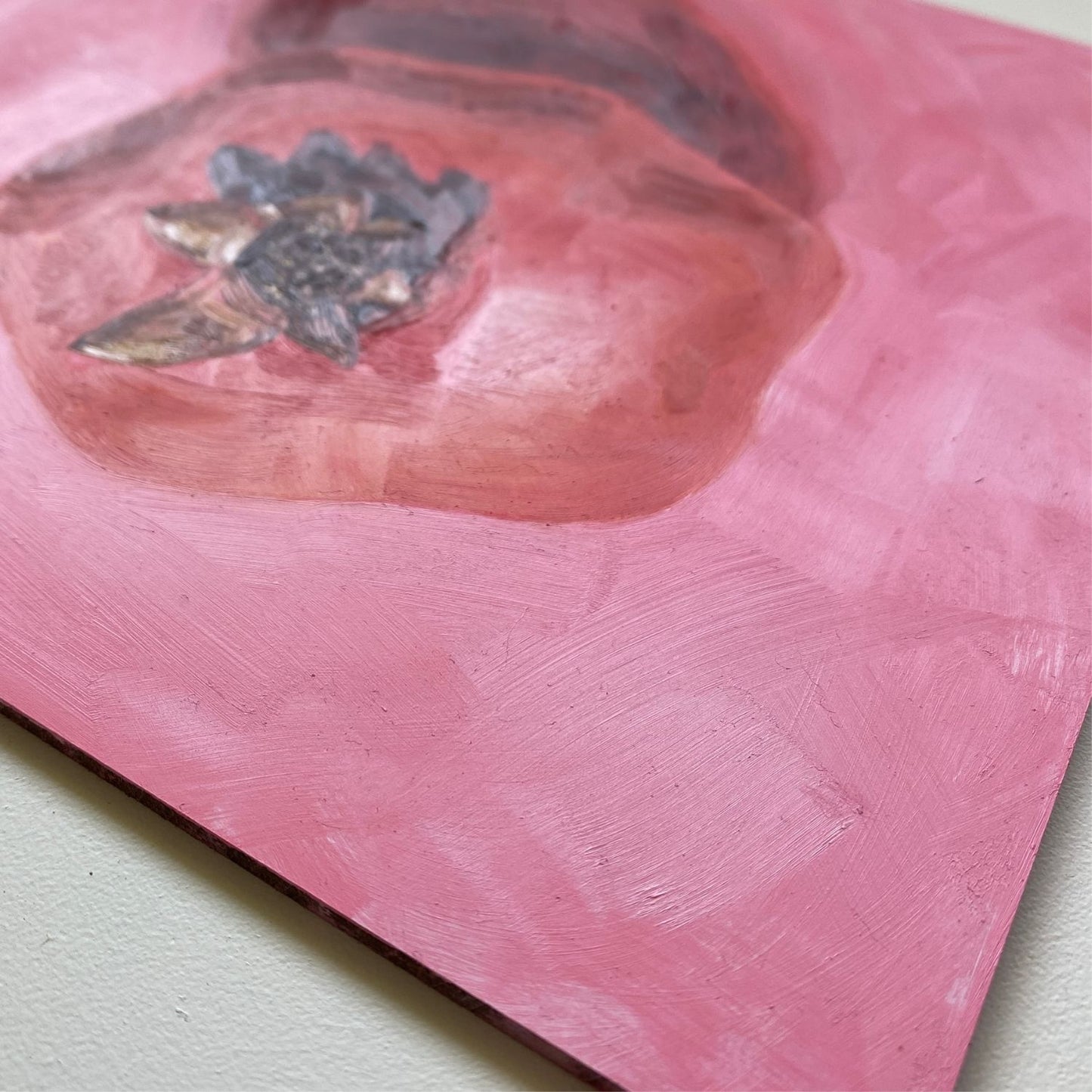 closeup of an original oil painting of a bright and vibrant red pomegranate with a strong reddish shadow on a textured pink background
