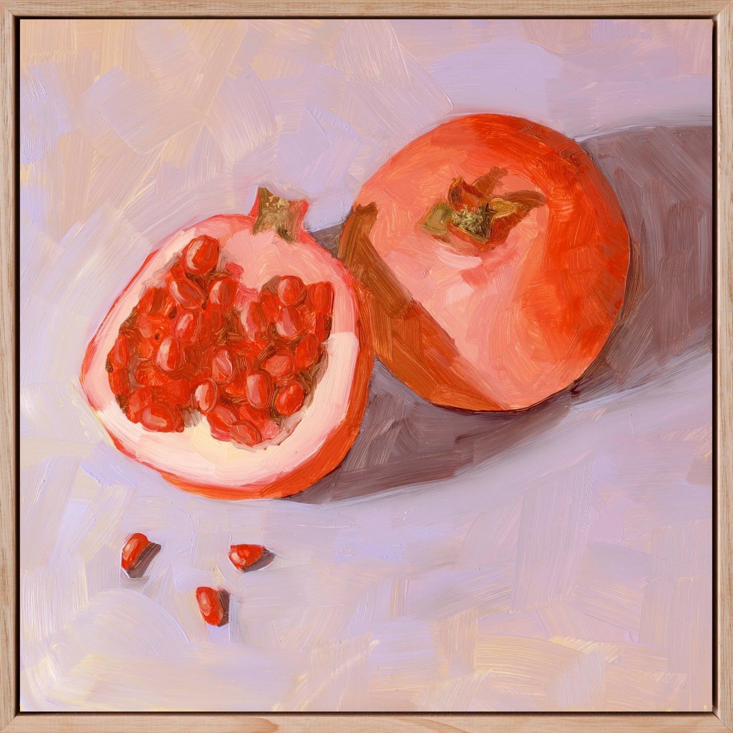 photo of a fine art timber framed canvas print of a full pomegranate and a cut pomegranate and seeds on a textured soft lilac background