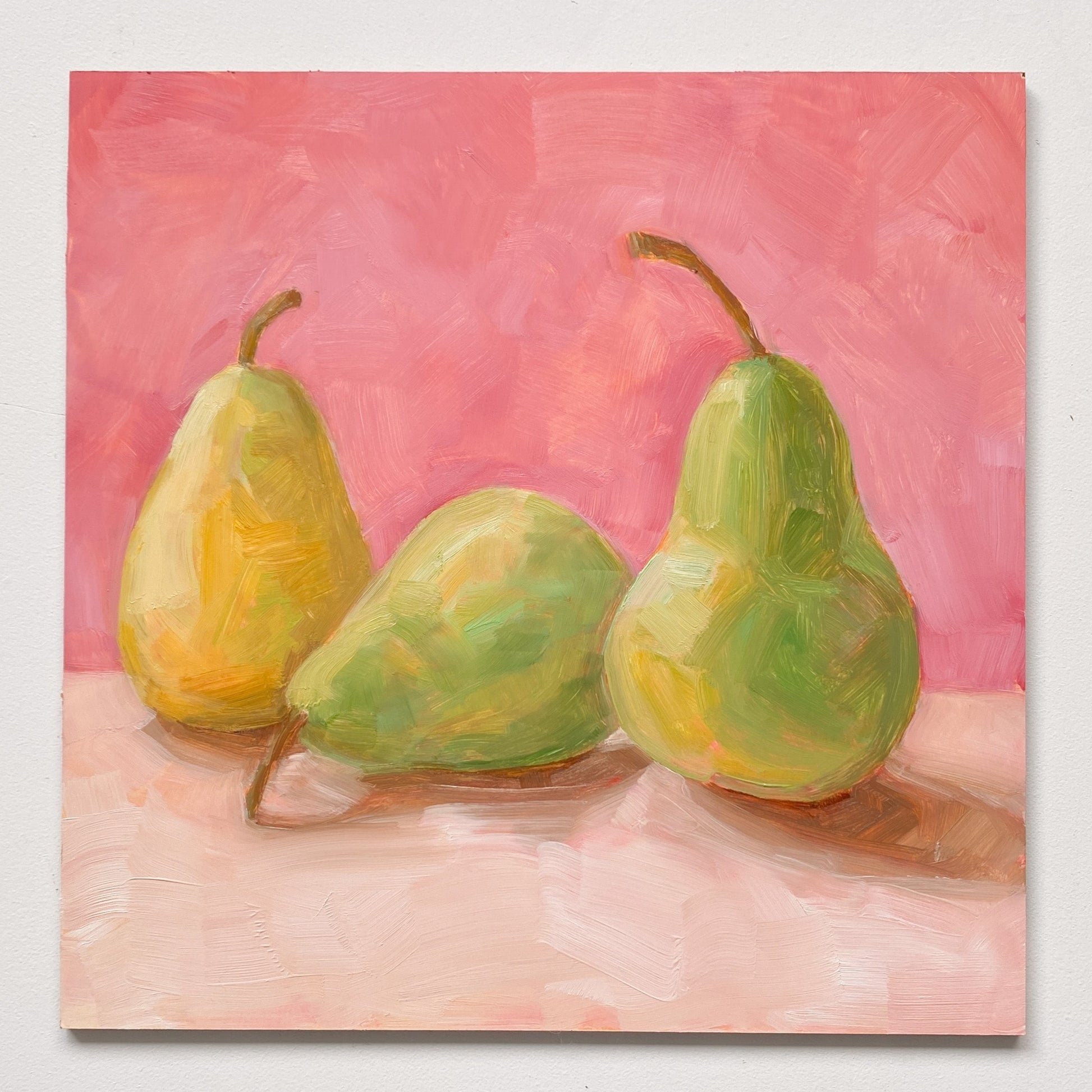 image of an oil painting of two green pears and one yellow pear on a cream surface with a soft and warm pink background
