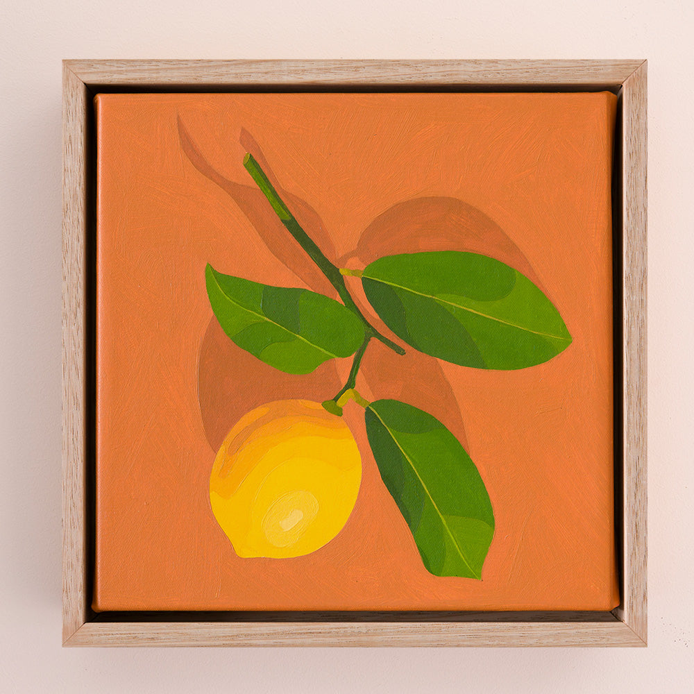 original oil painting of a lemon with stem and leaves sitting on a background of colour tan with darker tan shadow, framed in a raw oak shadow box